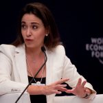 María Corina Machado, opposante vénézuélienne et lauréate du prix Nobel de la paix 2025, s’exprimant lors d’un panel du World Economic Forum, vêtue d’un tailleur blanc et parlant avec énergie devant un micro.
